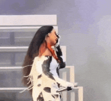a woman in a cow print outfit is holding a microphone on a stage .