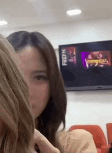 a couple of women are sitting next to each other in front of a tv .