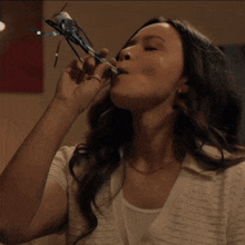 a woman in a white shirt is smiling and holding a bottle