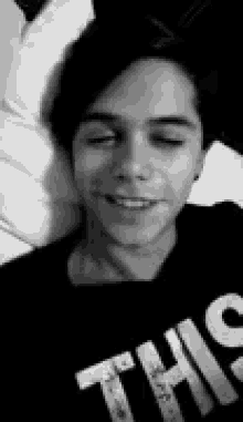 a black and white photo of a young man wearing a t-shirt that says `` this '' .