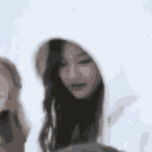 a woman wearing a white hoodie with a hood is standing next to another woman .