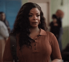 a woman in a brown dress is standing in a room with a backpack .