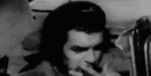 a man is smoking a pipe in a black and white photo .