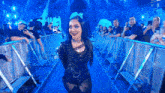 a woman in a black dress is standing in front of a crowd of people .