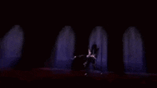 a man is kneeling down in a dark room holding a sword .