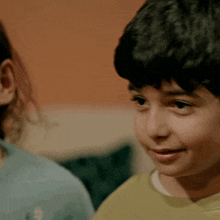 a young boy in a yellow shirt looks at the camera