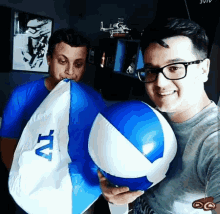 a man is holding a blue and white beach ball with tv on it