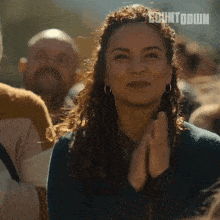 a woman applauds in a crowd with countdown written on the bottom