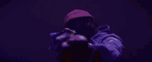 a man in a red hat is giving the middle finger in the dark .