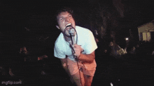 a man is singing into a microphone with his mouth wide open
