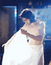 a shirtless man wrapped in a white towel looks down