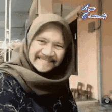 a woman wearing a hijab is smiling in front of a sign that says agus community on it
