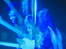 a man is playing a guitar in a dark room in a blue light .