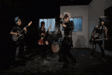 a group of people are playing guitars and dancing in a dark room