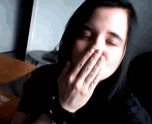 a woman covering her mouth with her hand while wearing a watch