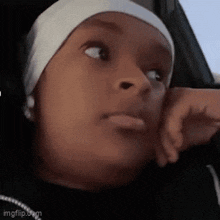 a woman wearing a headband is sitting in a car with her hand on her face .