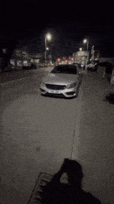a silver mercedes is parked on the side of a street