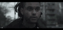 a man with dreadlocks and a beard is looking at the camera .