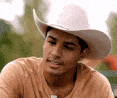 a man wearing a white cowboy hat and a brown shirt