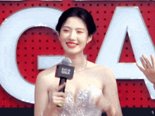 a woman in a white dress holds a microphone in front of a large ca sign
