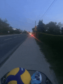 a yellow mikasa volleyball sits on the side of the road