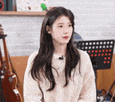 a woman in a white sweater with a microphone on her neck
