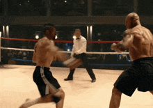 two men are boxing in a ring with a referee