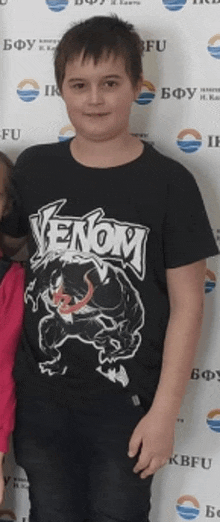 a young boy wearing a venom t-shirt stands next to a girl