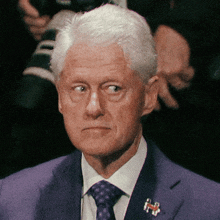 a man wearing a purple suit and tie has a pin on his lapel that says ' autism ' on it