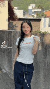 a woman wearing a white t-shirt with the word chf on it stands in front of a wall
