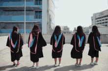a group of women in graduation gowns are standing in front of a building with the letter u on it
