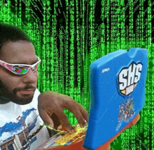 a man wearing sunglasses is typing on a blue shs laptop