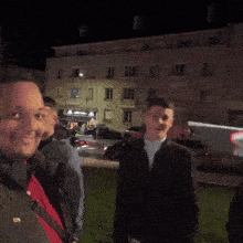 two men are standing in front of a building at night