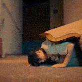 a woman is laying on her stomach on the floor with a blanket over her head .