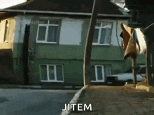 jitem is written on the sidewalk in front of a green building