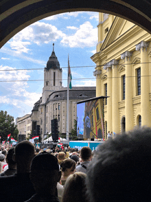 a crowd of people gathered in front of a yellow building