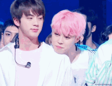 a man with pink hair stands next to another man