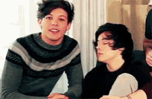 two young men are sitting next to each other in a room .