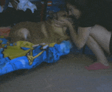 a woman hugging a dog on a bed with a spongebob blanket
