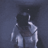 a woman wearing a hat and a white jacket is standing in a dark hallway