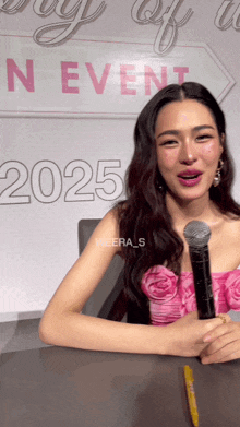 a woman holding a microphone in front of a sign that says n event 2025