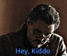 a man wearing glasses and a beard says hey kiddo