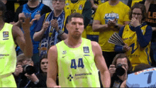 a basketball player wearing a number 44 jersey stands in front of a crowd