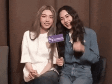 two women are sitting next to each other and one of them is holding a sign that says ' a ' on it .