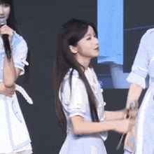 a girl in a blue dress holds a microphone