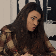 a woman wearing a plaid jacket with a red button