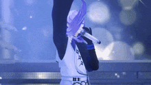 a man with purple hair is singing into a microphone on a stage .