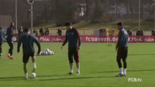 a group of soccer players are practicing on a field with an advertisement for fc bayern.de in the background