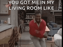 a man in a red sweater is jumping in the air in a living room .
