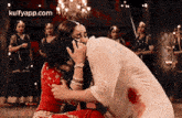 a woman is kissing another woman on the cheek in front of a group of women .